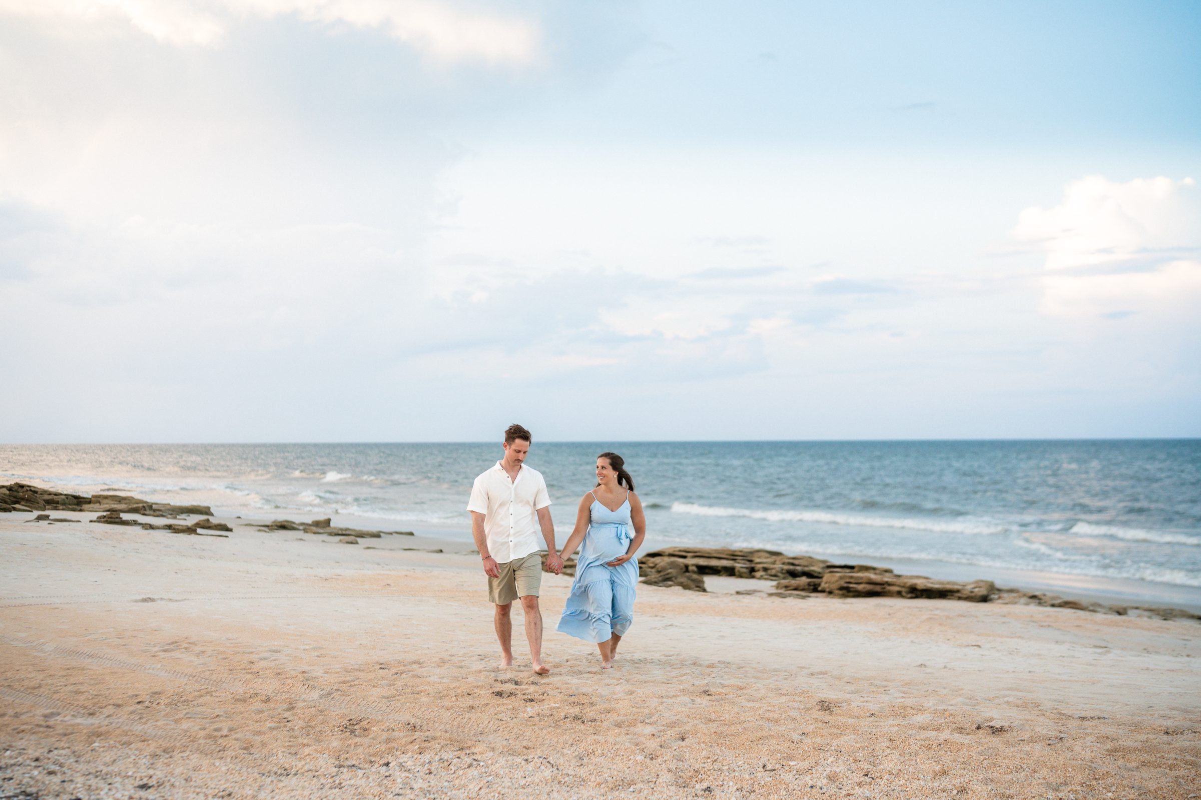 Expecting couple embracing on the beach during a Florida maternity session